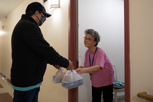 An AHRC NYC volunteer delivering a meal to a homebound elderly woman. 