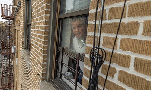 Citymeals on Wheels recipient Bernito looking out the window of his Bronx apartment. 