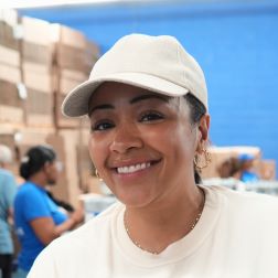 Citymeals volunteer Jessica packing meals for seniors in NYC. She wears a white hat and tee. 
