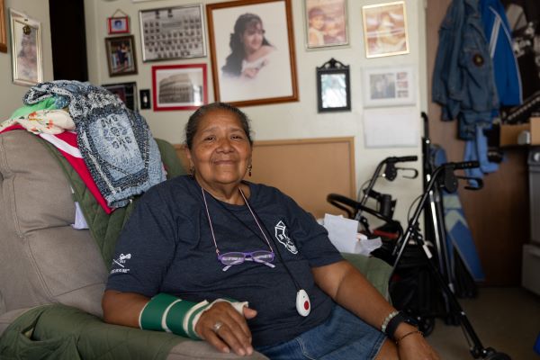 A Hispanic woman in a cast sits in an armchair.