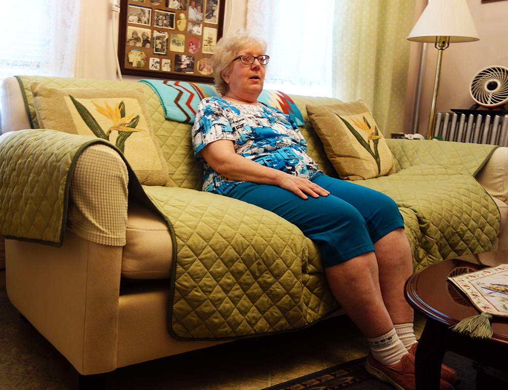 Citymeals on Wheels recipient Jackie sits by her air conditioner. Heat waves make her health conditions worse. 