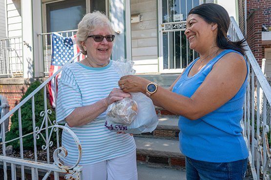 Citymeals deliverer Veronica hands a meal to Jackie, a senior living in Queens New York. 