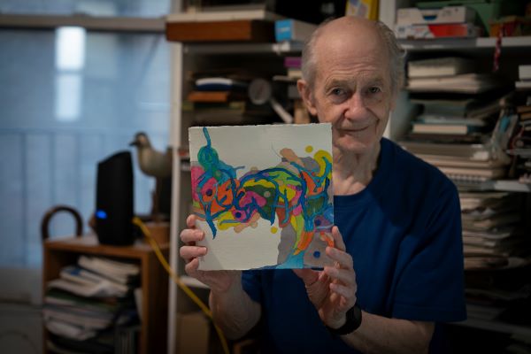 Giora holding up one of his paintings. 