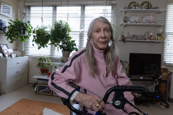 Joan sits on her walker in her apartment.