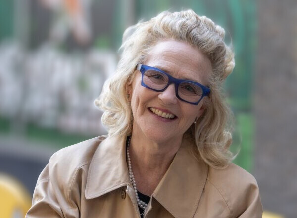 A woman with blue glasses smiles at the camera. 