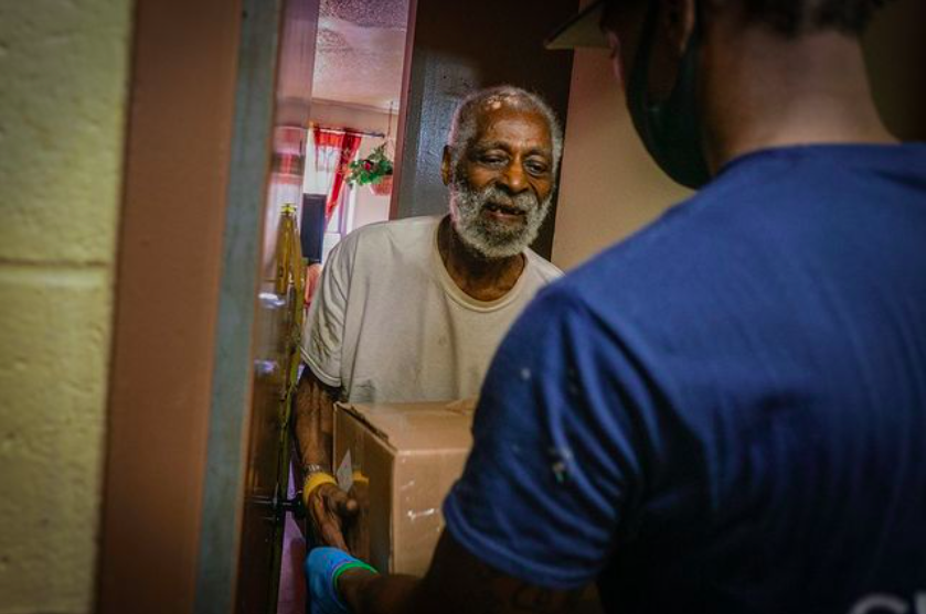 A meal recipient accepting a nutritious delivery.