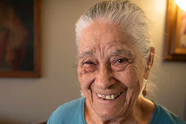 Vicenta, Citymeals recipient, an older woman with light skin and white hair in blue shirt. She is smiling.