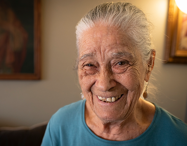 Vicenta, Citymeals recipient, an older woman with light skin and white hair in blue shirt. She is smiling.