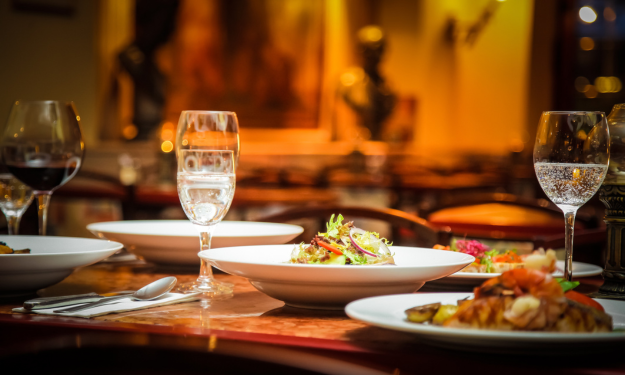 glass of wine on table with meal. Nighttime scene. 