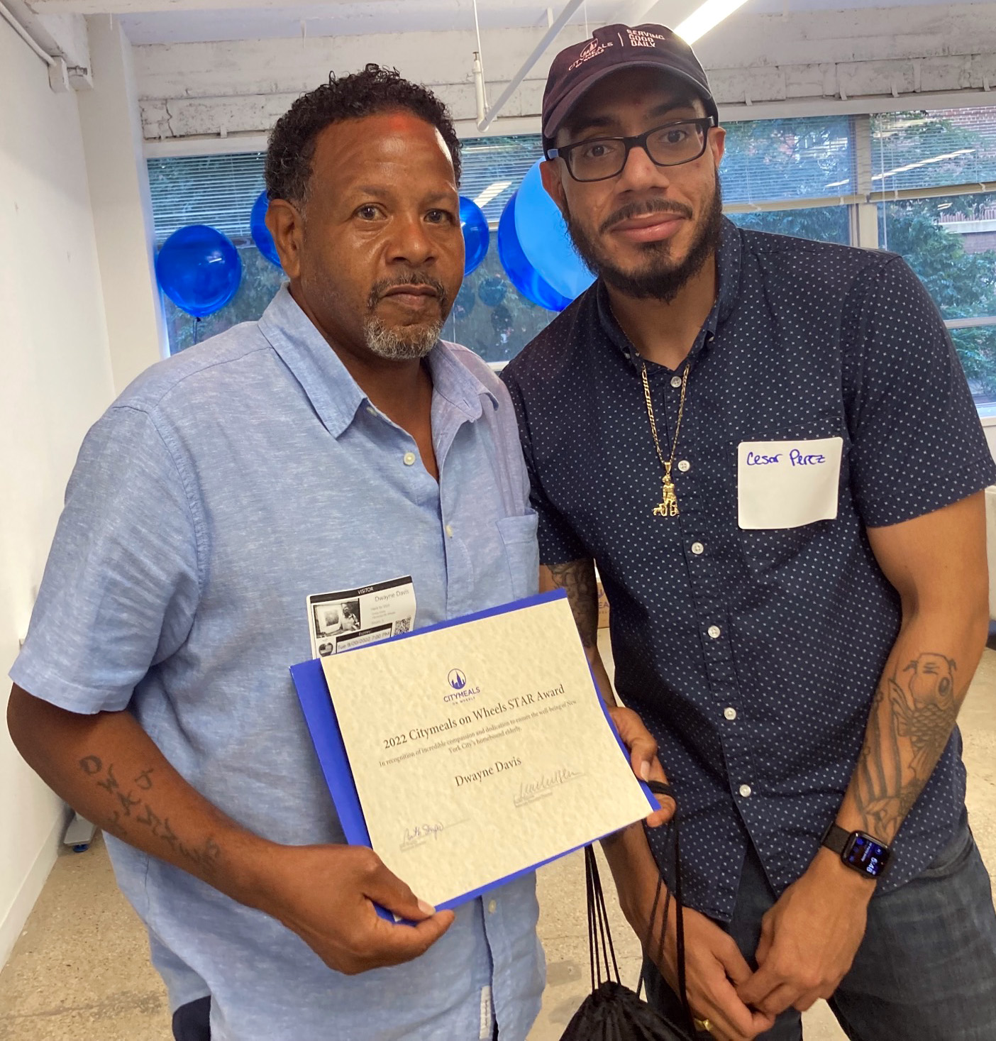 Dwayne, a middle-aged African-American man, poses with his award with Citymeals staff member.