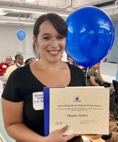 Dhianne Madera, a young woman with dark hair, holds her award certificate and smiles. 