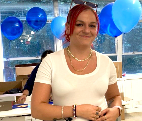 Josie, a young woman in a white t-shirt with red hair, holds her award certificate