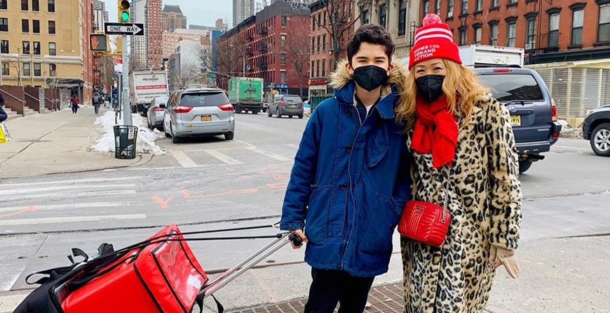 A mother and son in winter coats and hats delivering meals to homebound elderly New Yorkers. 