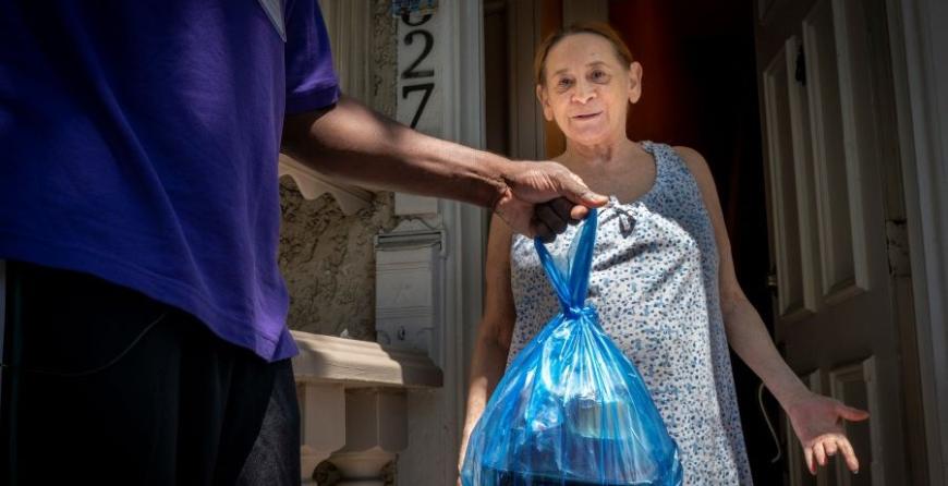 A woman in a short-sleeved dress receiving a meal at the door. 