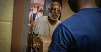 Photo of volunteer delivering a nourishing meal to a homebound elderly New Yorker. 