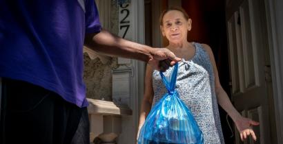 A woman in a short-sleeved dress receiving a meal at the door. 