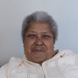 An older woman looking directly into the camera and smiling.