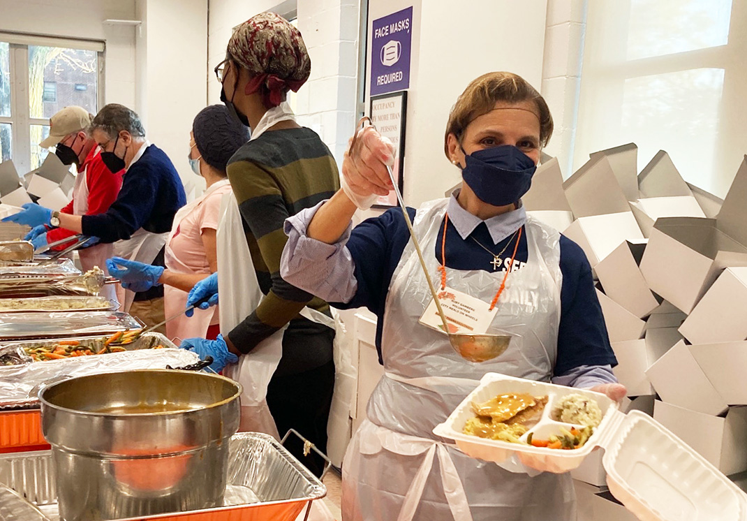 Citymeals volunteer Ruby adds gravy to a Thanksgiving meal. 